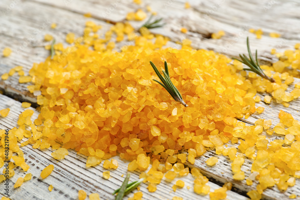 Heap of orange sea salt on light wooden background, closeup