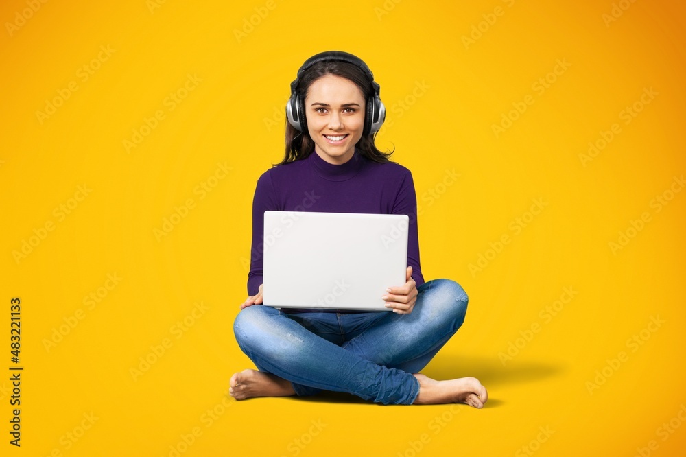 Beautiful young smiling woman in casual outfit sitting and working on her laptop.