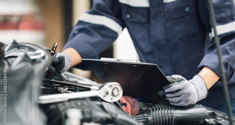 Mechanic works on the engine of the car in the garage. Repair service. Concept of car inspection ser