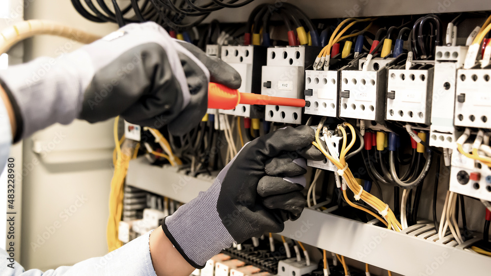 Electricians work to connect electric wires in the system, switchboard, electrical system in Control