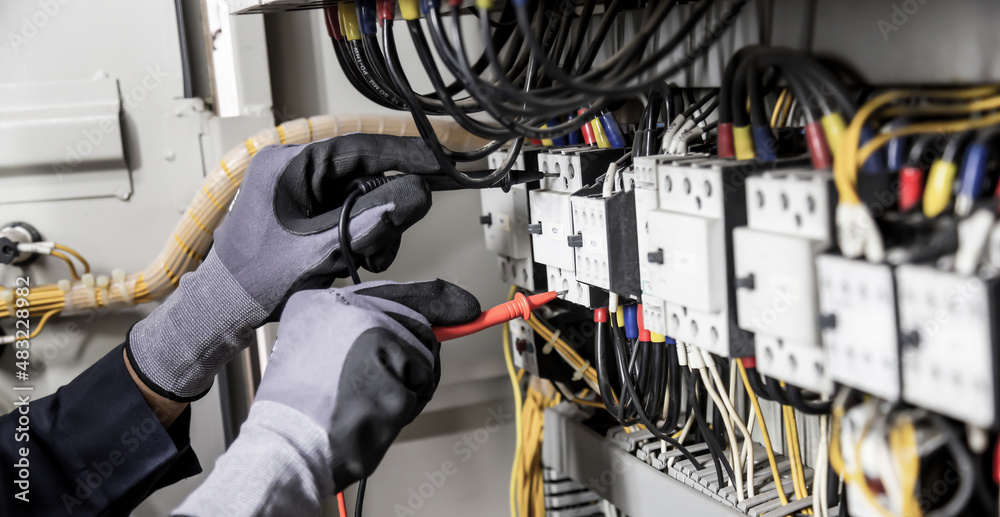 Electrician engineer tests electrical installations and wires on relay protection system. Adjustment