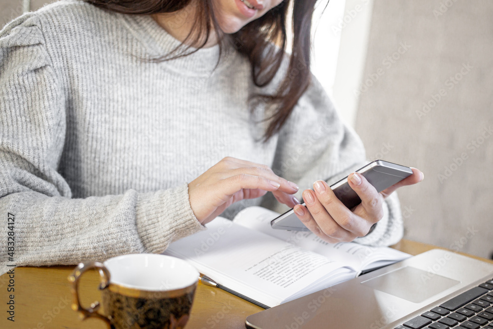 Portrait of a businesswoman sitting on her workplace in the office, typing, looking at phone screen,