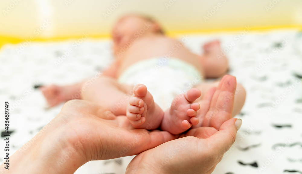 Newborn baby feet. Cute feet of sleeping baby. Mothers hands