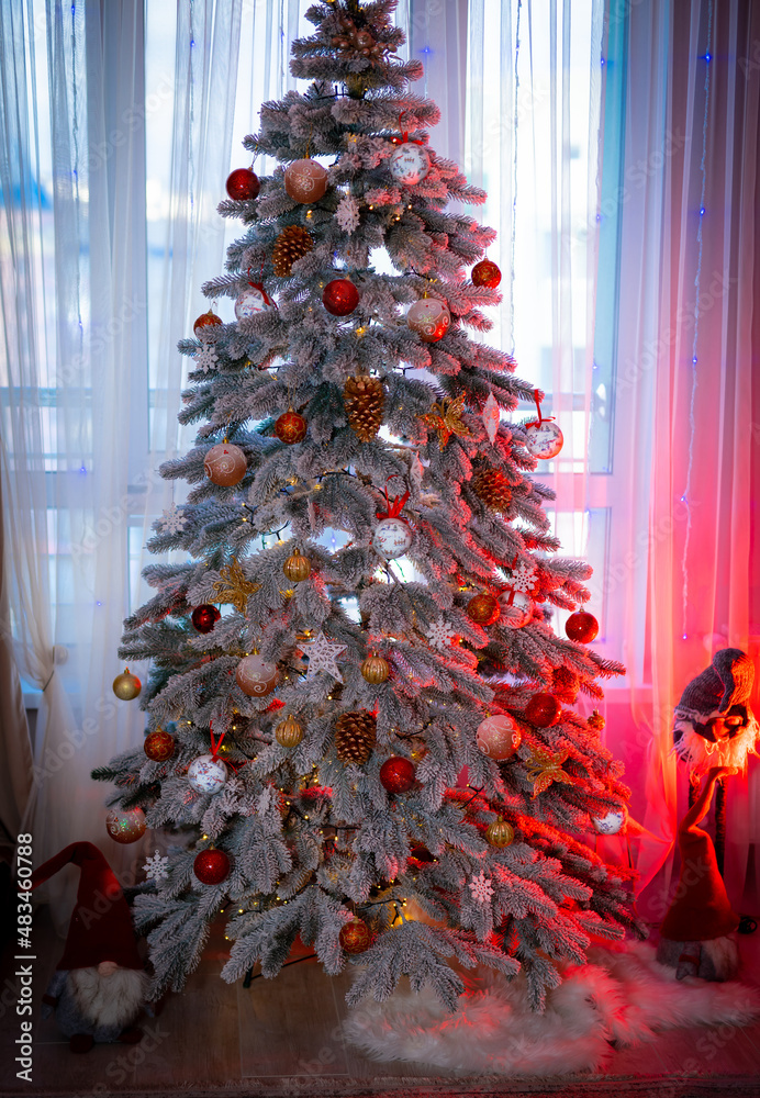 Christmas tree with lights and ribbons. Amazing fir tree decorated with Christmas balls near the coz