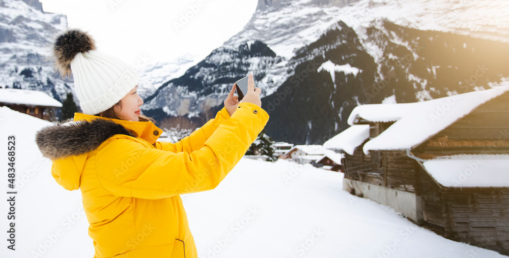 Grindelwald瑞士欧洲之巅，亚洲女子穿着黄色外套。她用智能手机拍了一个p