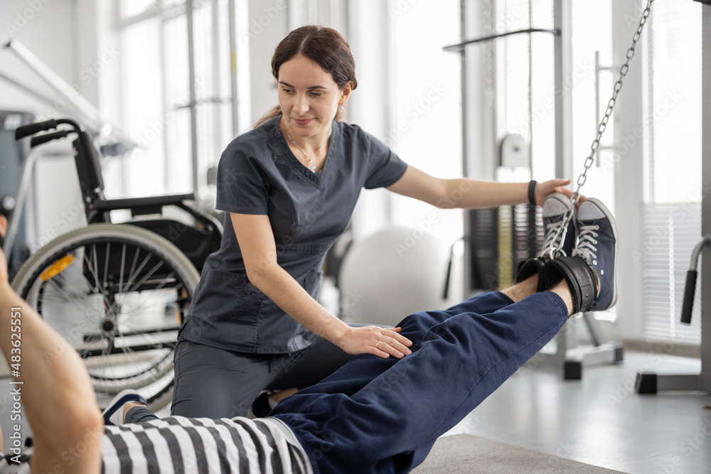 Rehabilitation specialist helps a guy to do exercise on decompression simulator for recovery from in