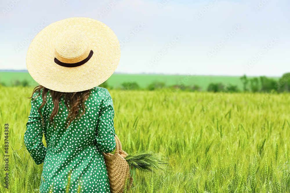 Woman with bag in green wheat field on sunny day