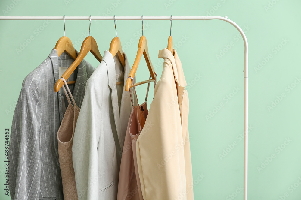 Rack with clean female clothes on green background, closeup