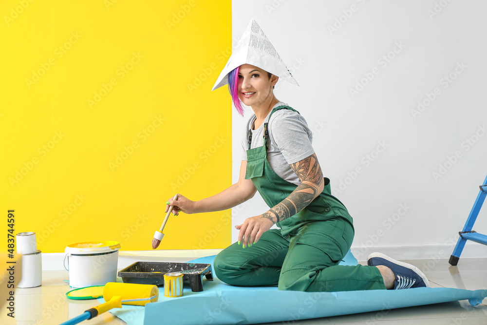 Female painter with brush sitting near color wall