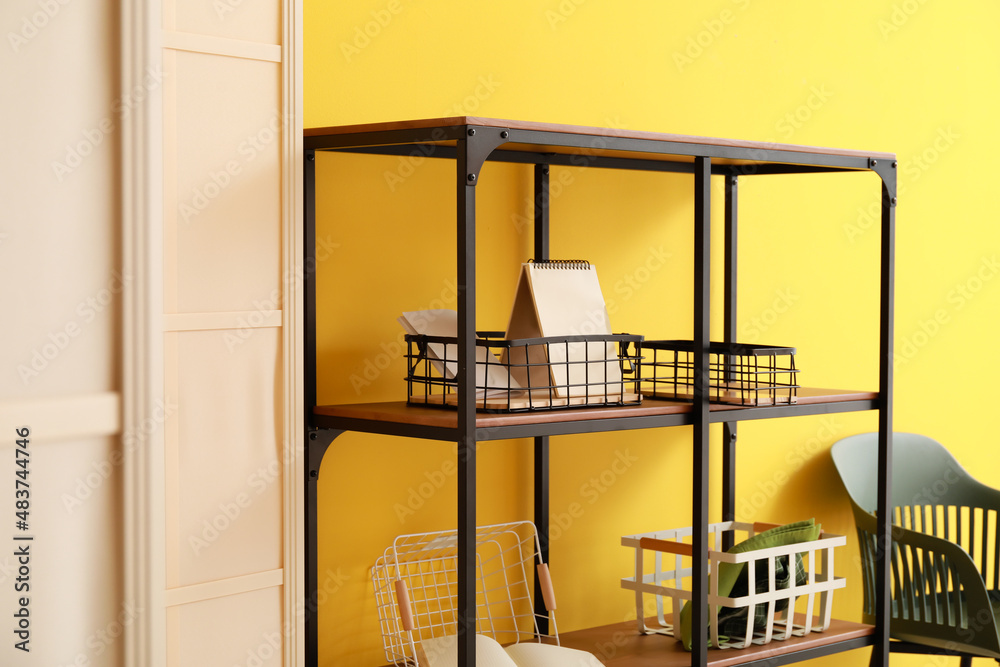 Shelf unit with baskets near color wall, closeup