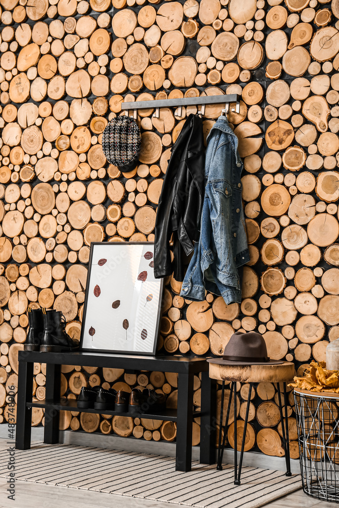 Stand with shoes and picture frame near wooden wall in hallway