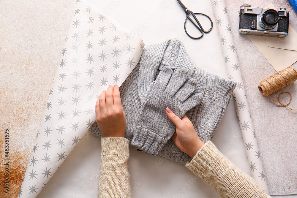 Woman wrapping sweater and gloves on light table