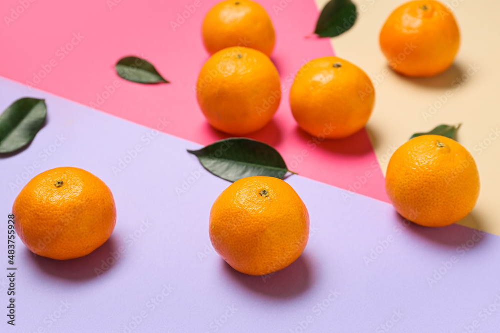 Sweet tangerines and leaves on color background, closeup