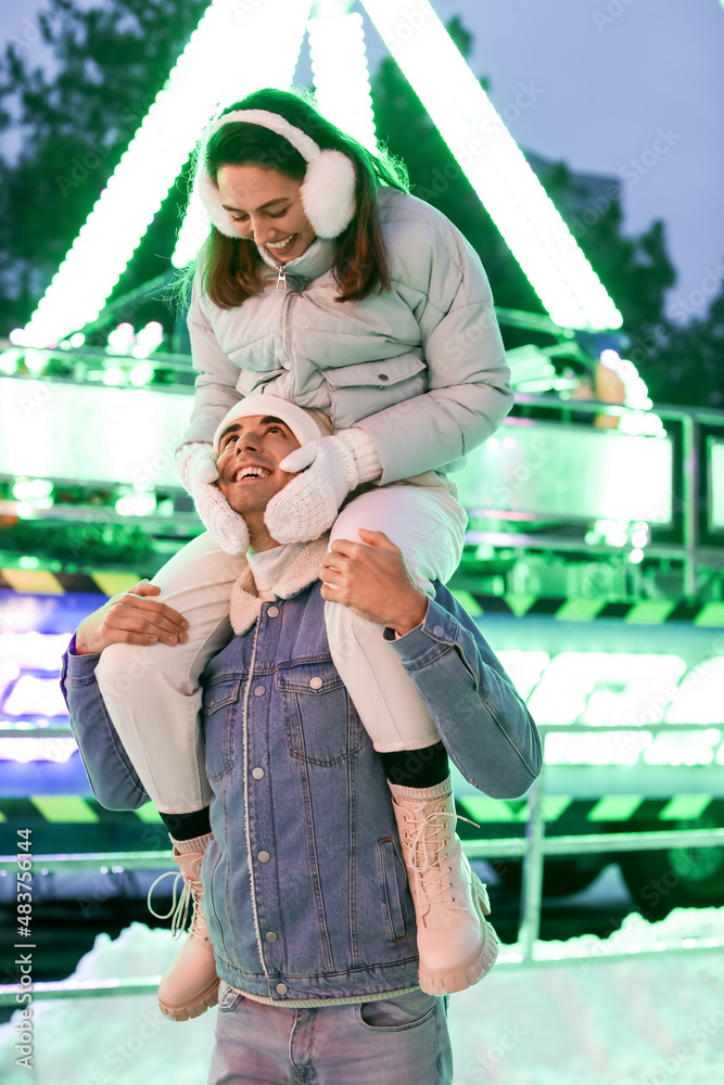 Loving couple in amusement park at winter night