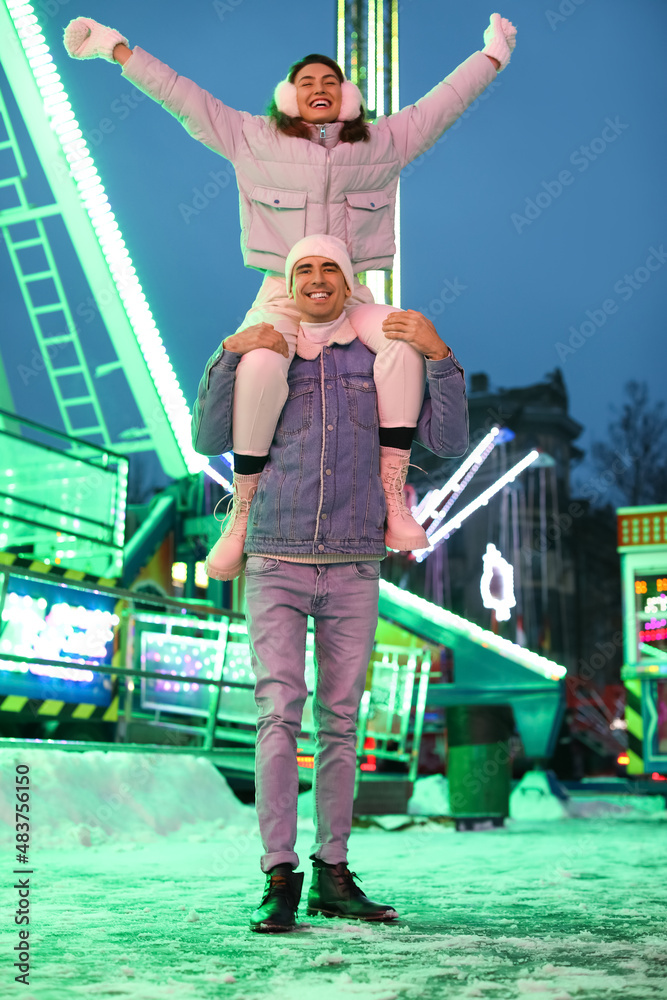 Loving couple in amusement park at winter night