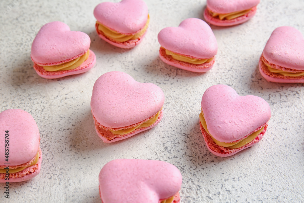 Tasty heart-shaped macaroons on light background