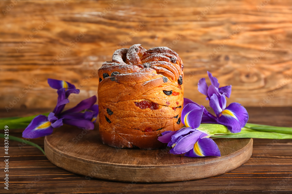 Board with delicious Easter cake and irises on wooden background