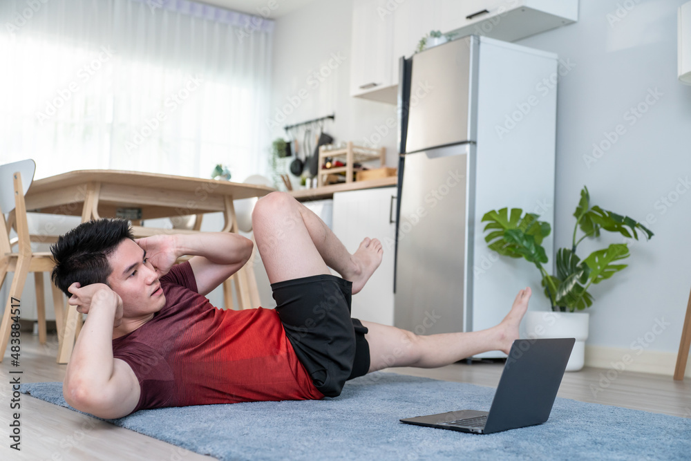 Asian active young man doing yoga exercise on floor in living room. 