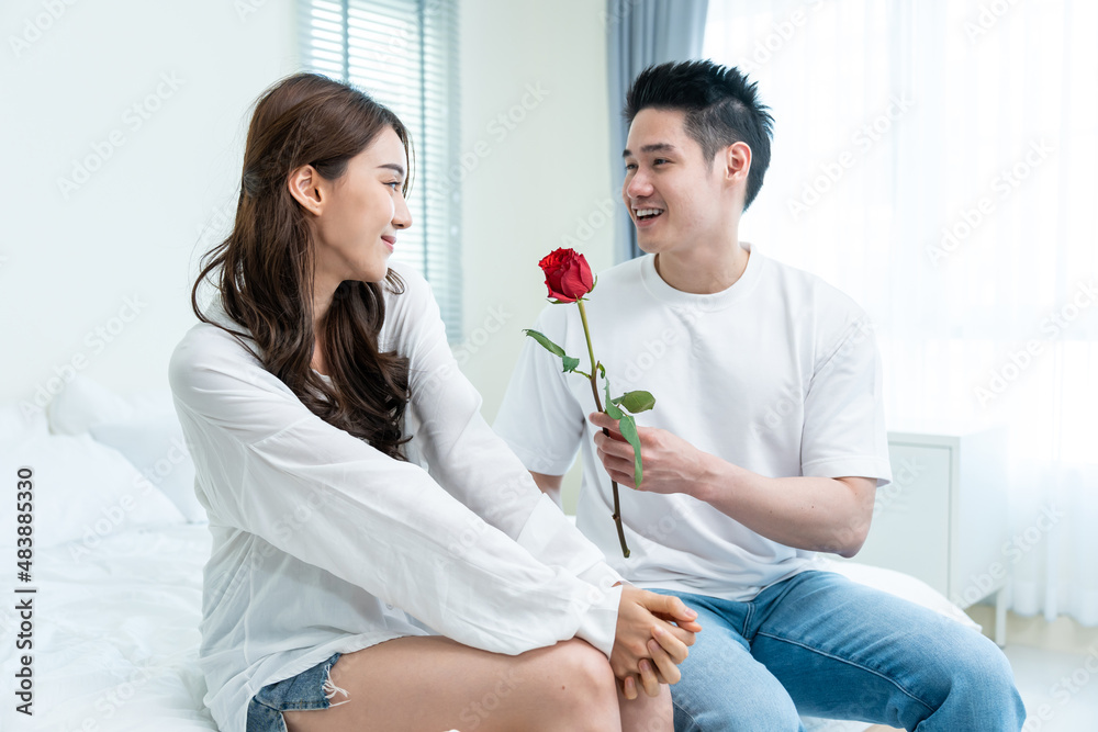 Asian young man surprise and give rose flower to beautiful girlfriend. 