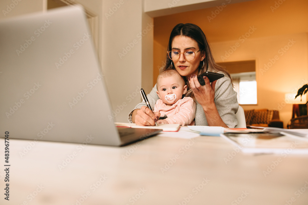 Working mom making notes during a phone call