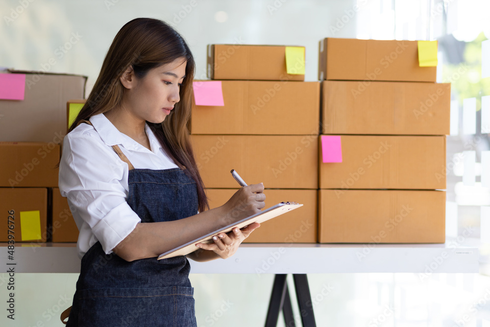 Small business owner woman holding a notepad with a list of items and orders.