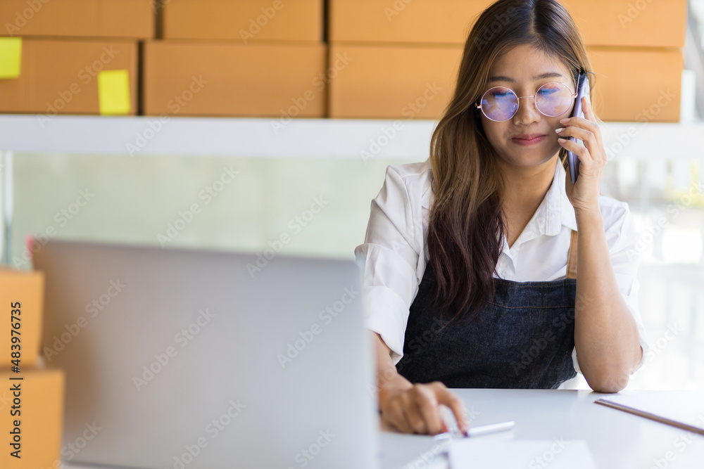 在线小企业主。一位在办公室工作的女士正在与一位客户通电话。