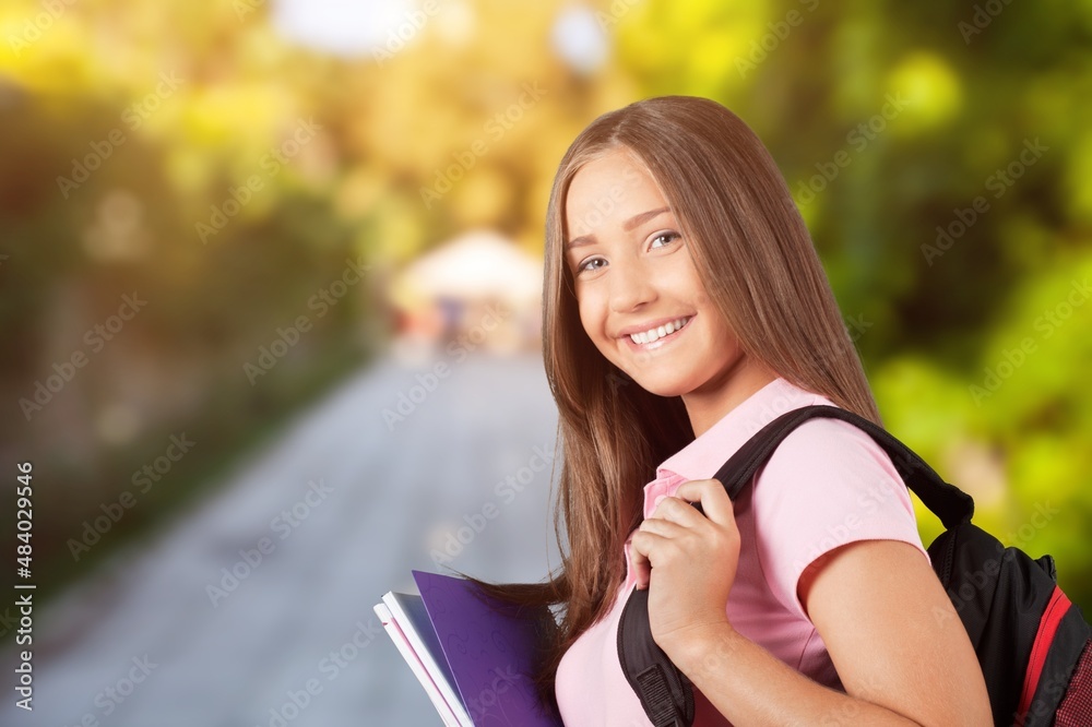 Female student standing outdoors university holding books.