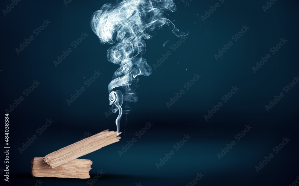 sacred incense stick on a background with a fire and a lot of smoke. The concept of incense, healing