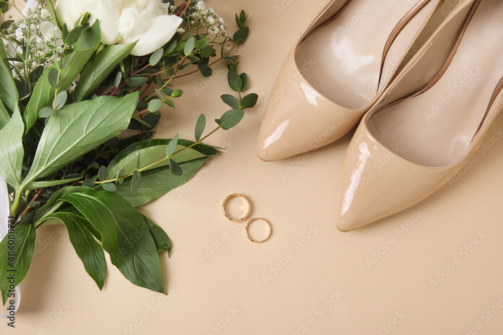 Wedding rings, flowers and shoes on light background