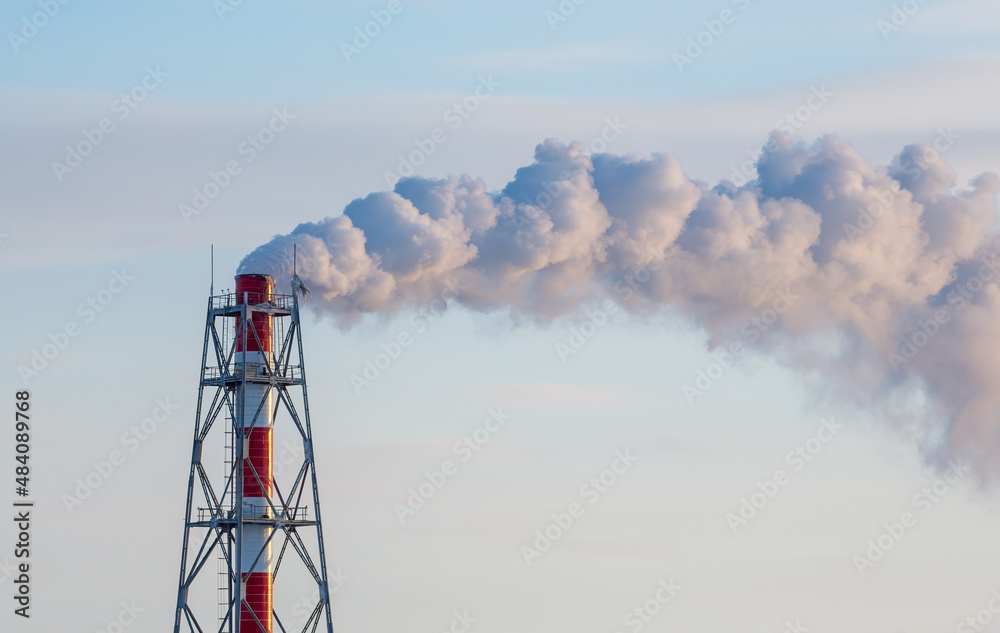 Power plant pipe and clouds of smoke close-up against the sky. Aerial view of high smoke stack with 