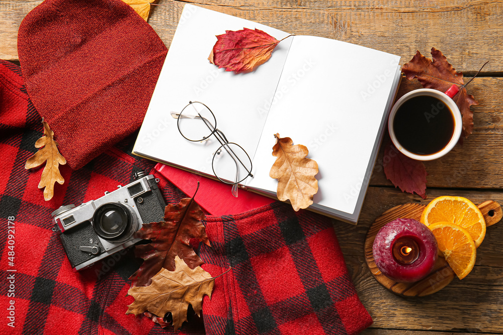 Blank book, cup of coffee, photo camera and autumn decor on wooden background