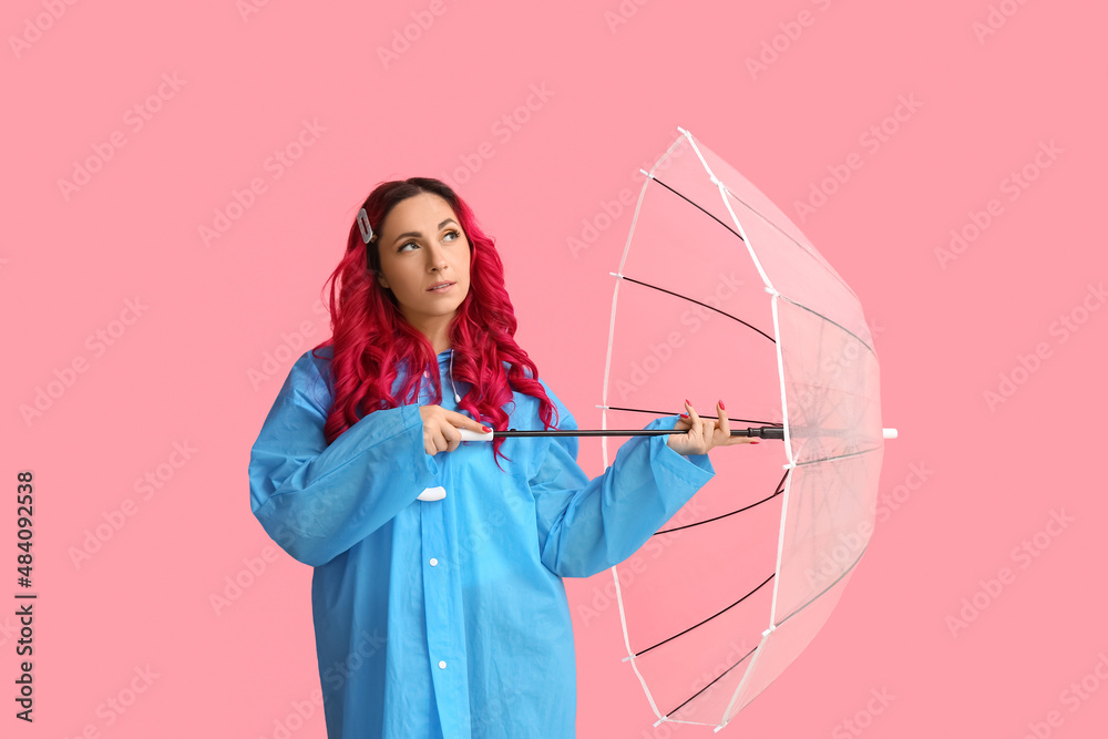 美丽的女人穿着雨衣，彩色背景上带着雨伞