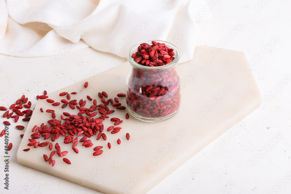 Jar with dried barberries on light background