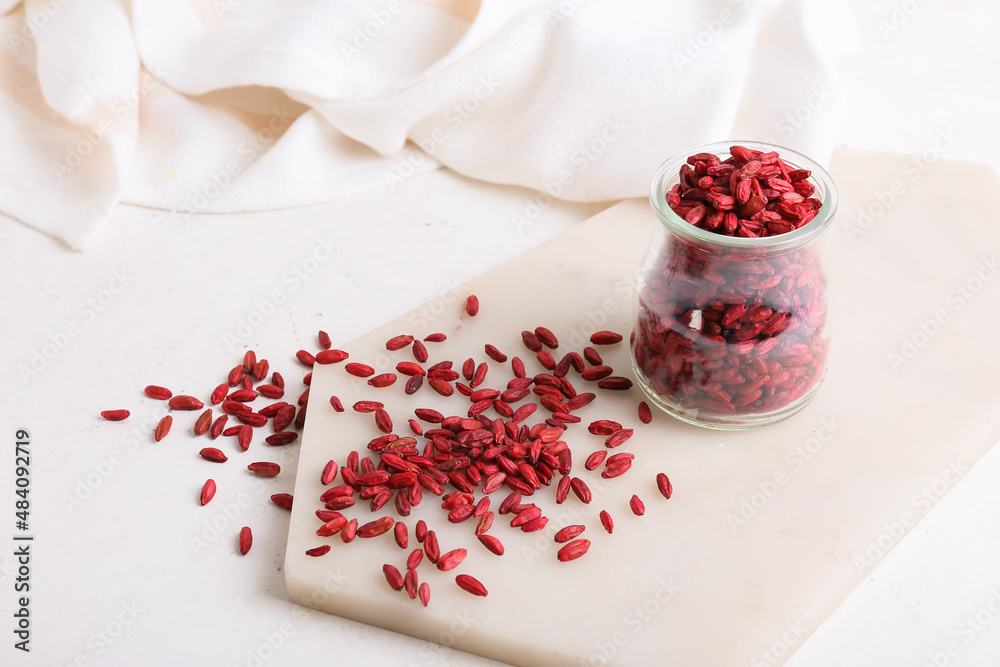 Jar with dried barberries on light background