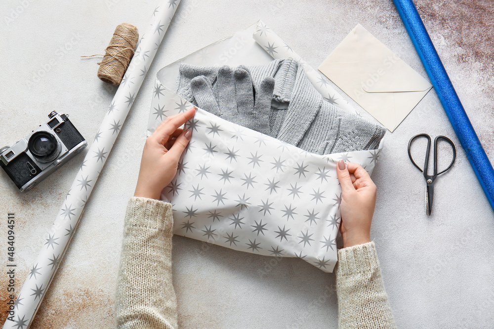 Woman wrapping gloves and sweater on table