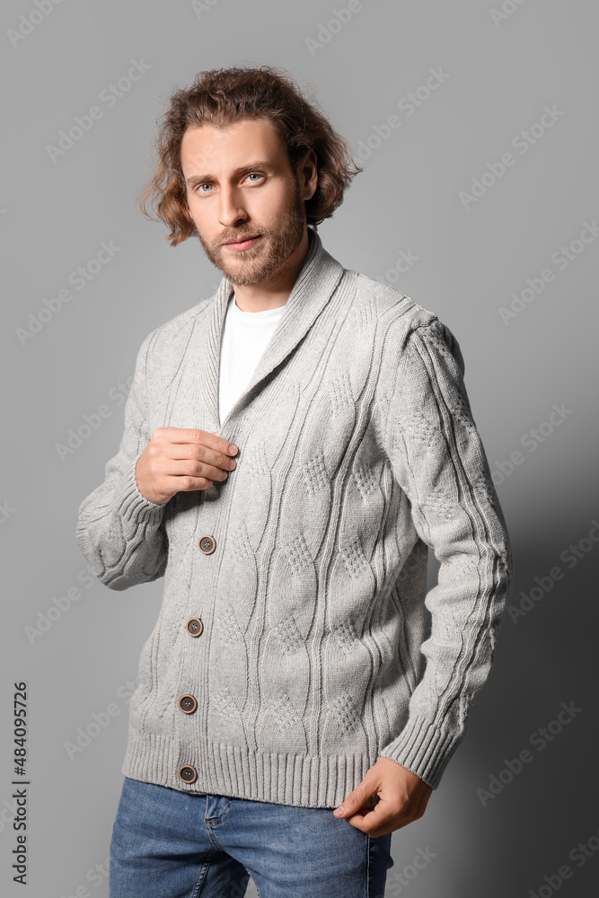 Handsome young man in knitted sweater on grey background