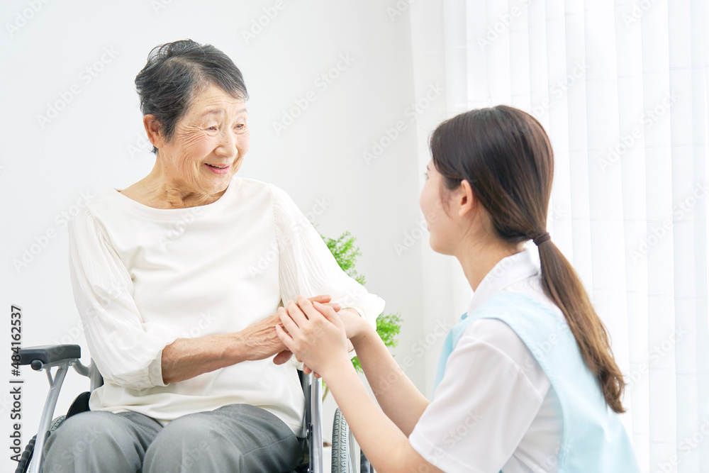 介護士と車椅子に乗る高齢者　室内