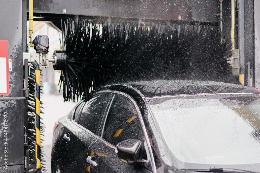 car washer washing car in parking lot