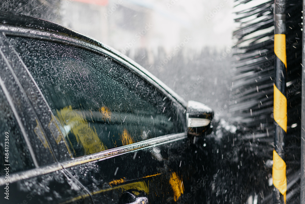 car washer washing car in parking lot