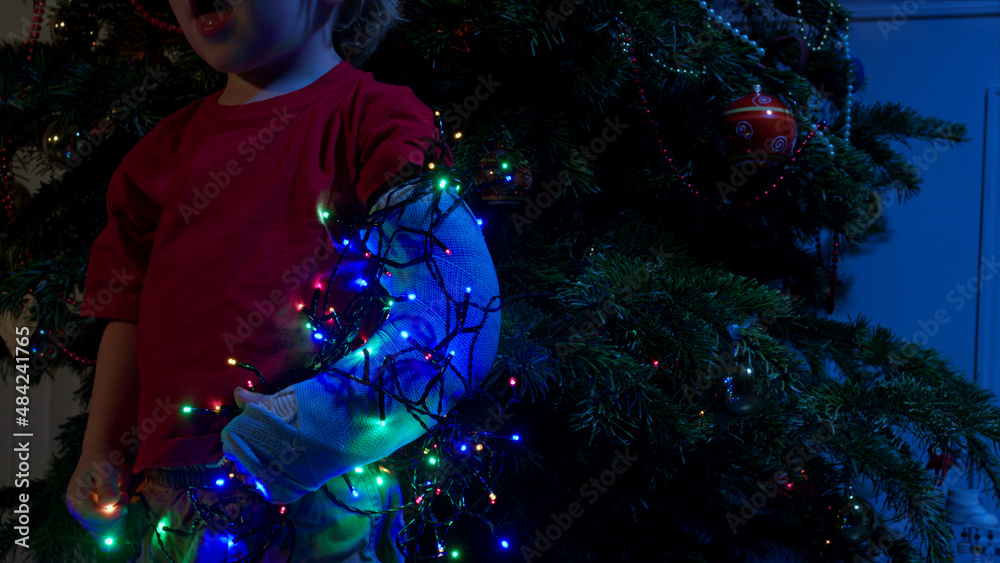 Broken toddler hand in cast illuminated by garland