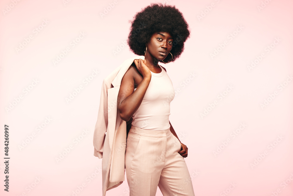 Stylish woman standing on a pink background