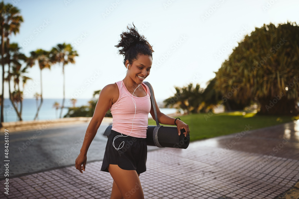 Smiling young woman in sportswear walking to yoga class