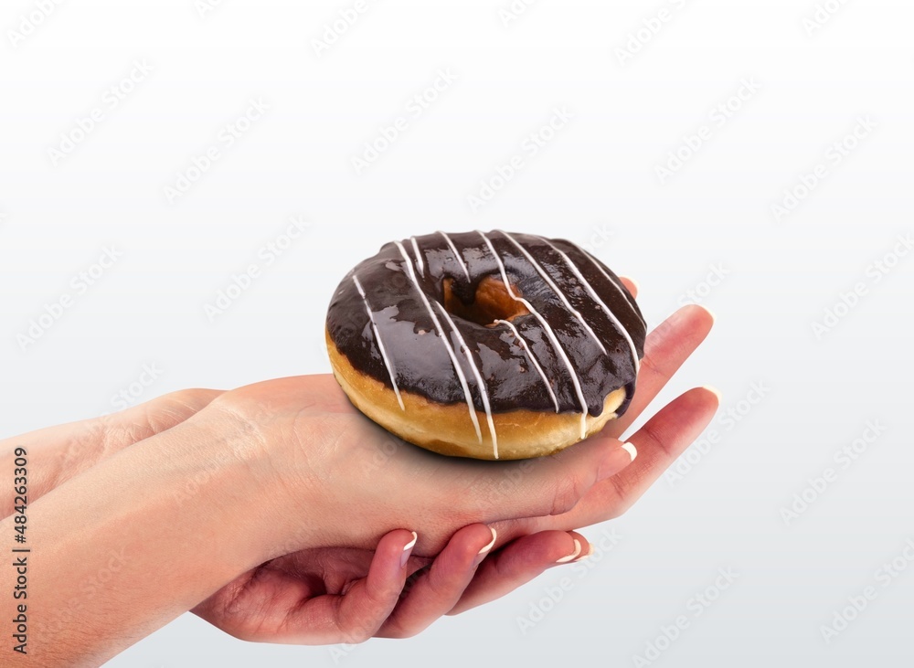 Hand holds Hanukkah donut with jam on the background.