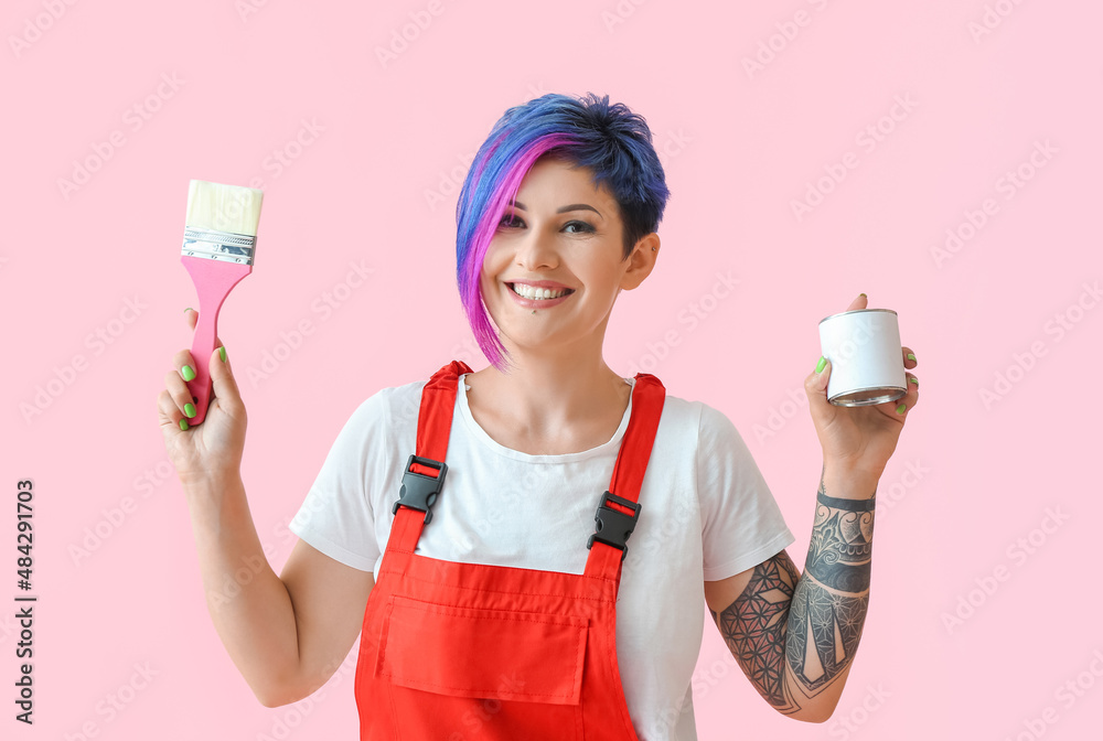 Female painter with brush and can of paint on pink background