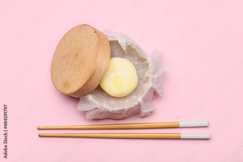 Wooden box with delicious mochi and chopsticks on color background