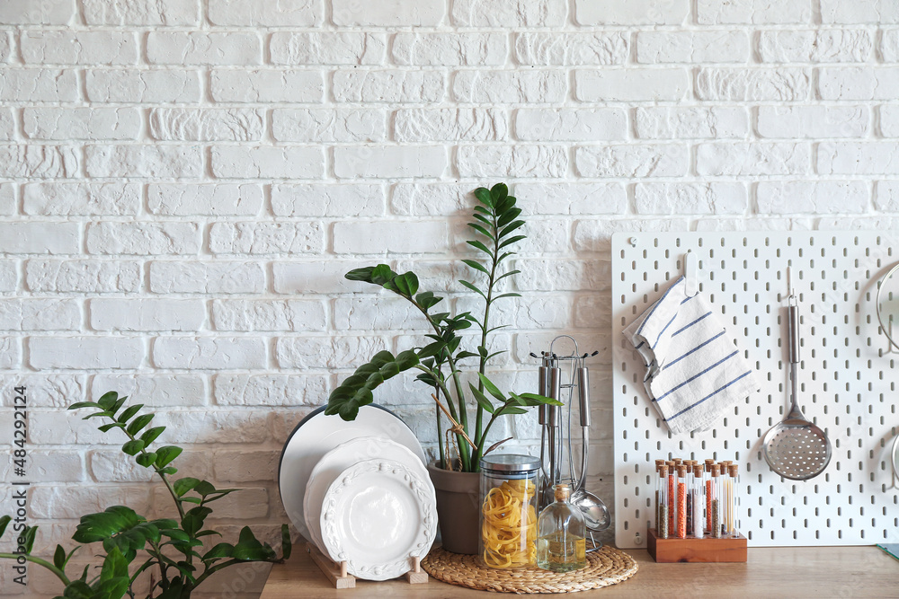 Kitchenware and houseplants on counter near white brick wall