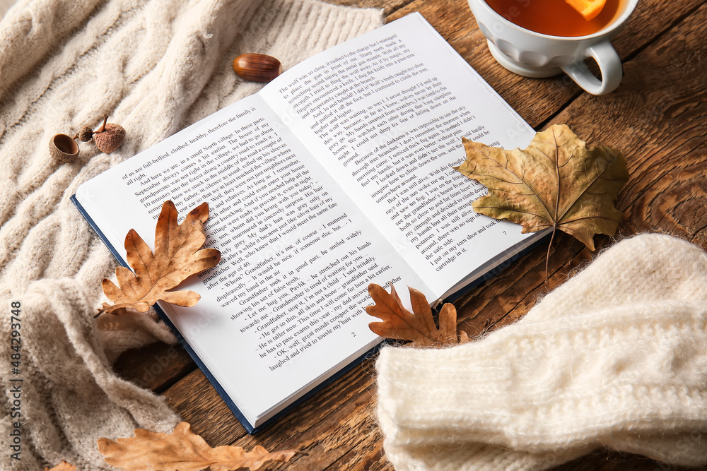 Book, cup of tea, clothes and wooden background, closeup