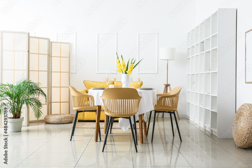 Interior of light dining room with beautiful table setting and vase with Gladiolus flowers