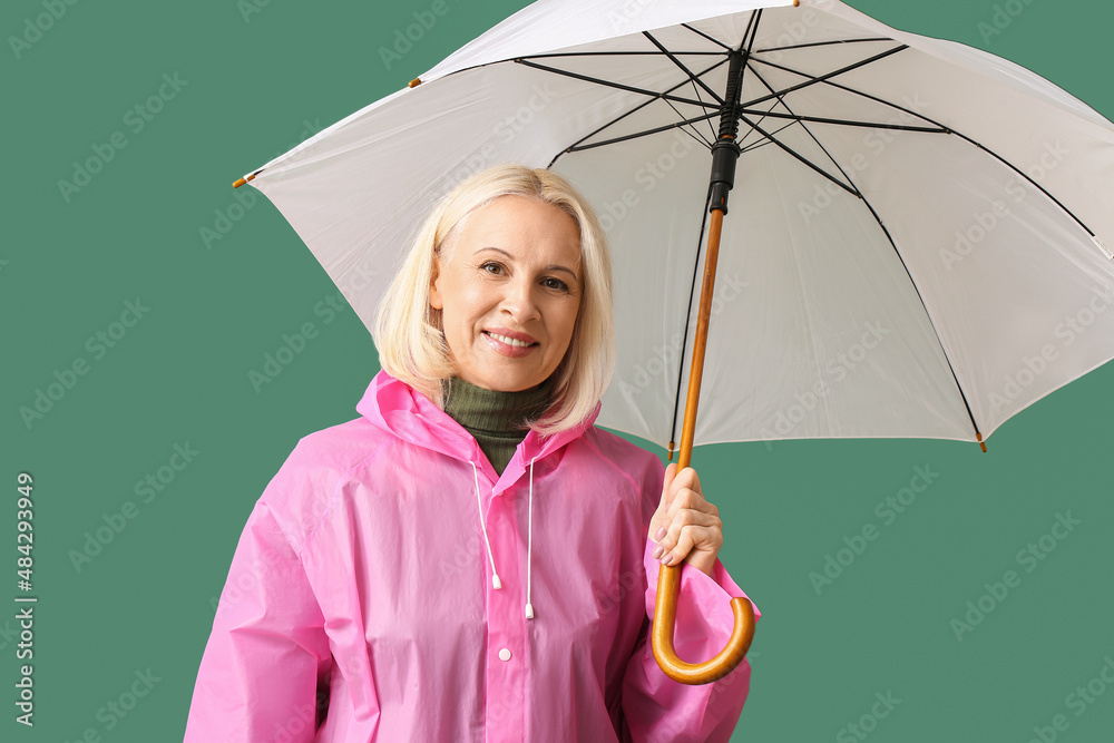 美丽的成熟女人穿着雨衣，颜色背景上有雨伞