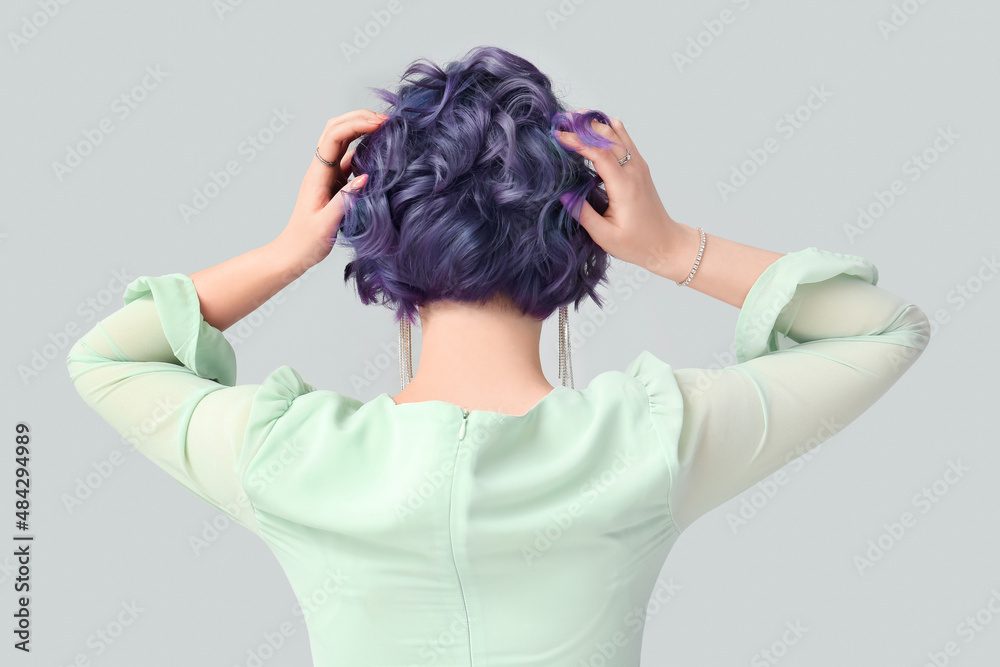 Beautiful young woman with violet hair on light background, back view. Very Peri - color of year 202